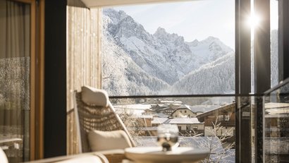 Blick von einem Balkon auf verschneite Berge und Häuser im Tal