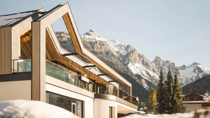Modernes Chalet in den Alpen mit schneebedeckten Bergen im Hintergrund