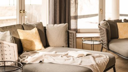 Cozy seating area with gray sofa, cushions and open book by window
