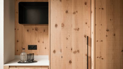 Holzschrank mit Griff auf Küchenarbeitsplatte mit Glasflasche und Gläsern