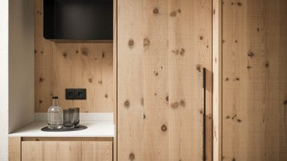 Holzschrank mit Griff auf Küchenarbeitsplatte mit Glasflasche und Gläsern