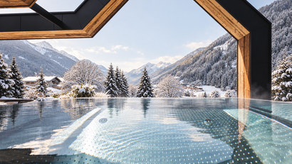 Beheizter Außenpool mit Blick auf ein verschneites Alpental
