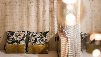 Zwei gemusterte und zwei gelbe Kissen auf einem Sofa vor Holzwand