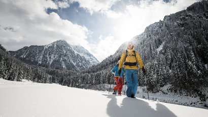 Zwei Wanderer mit Schneeschuhen in schneebedeckten Bergen bei Sonnenschein