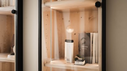 Holzregal mit Kosmetikprodukten und Werbematerial im Glasvitrine