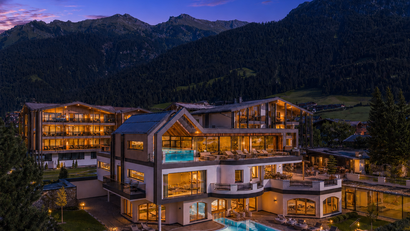 Beleuchtetes Hotel mit Pool und Bergblick bei Dämmerung