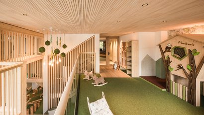 Kinderzimmer mit Holzdecke, Spielhaus und weichem grünem Teppich