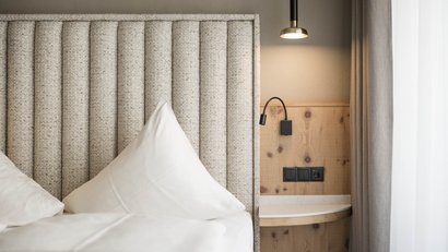 Moderner bettkopf mit leuchten und holz-nachttisch im schlafzimmer