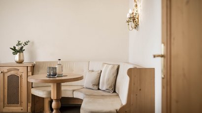 Gemütliche Sitzbank mit Tisch, zwei Gläsern und Blumenvase im hellen Raum