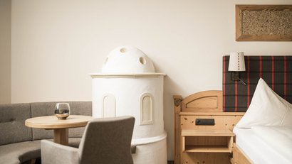 Gemütliche Ecke mit Ofen, Tisch, Stuhl und Bett im Landhausstil