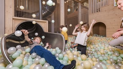 Kinder spielen in einer Bällebad-Spielhalle mit Rutsche