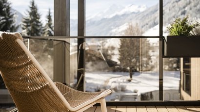 Balkon mit Stuhl und verschneiter Berglandschaft im Hintergrund