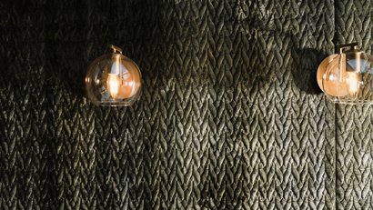 Wand mit gewebtem Muster und zwei goldene Wandlampen