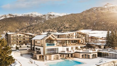 Modernes Hotel mit Pool in verschneiter Berglandschaft bei Sonnenlicht