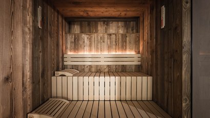 Moderner finnischer Sauna-Innenraum mit Holzverkleidung und beleuchtetem Rückenlehne