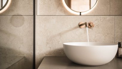 Moderner Badezimmerwaschbecken mit laufendem Wasserhahn vor kreidefarbenen Fliesen