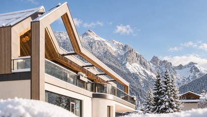 Modernes Alpenchalet vor schneebedeckten Bergen und verschneiten Bäumen