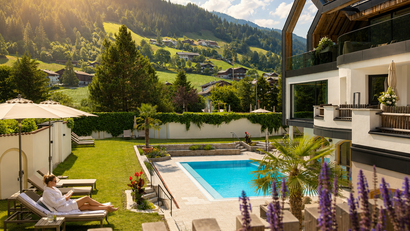 Frau entspannt auf Liegestuhl neben Pool in Bergresort bei Sonnenschein