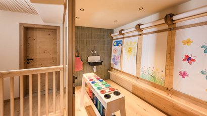 Hell gestalteter Malraum mit Staffelei und bunten Bildern an der Wand