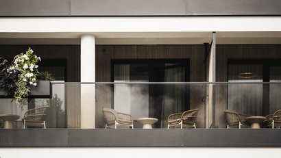 Moderner Balkon mit Stühlen und Blumen an einem Wohngebäude