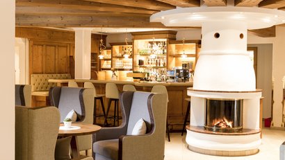 Gemütliche Bar mit Kamin und bequemen Sesseln in warmem Holzinterieur