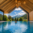 Person schwimmt in Pool mit Blick auf Berge und Wald unter Holzdecke