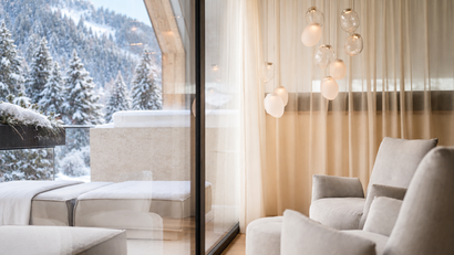 Gemütliche Sitzecke mit Sesseln und Pendelleuchten vor einem Fenster mit Blick auf verschneite Bäume