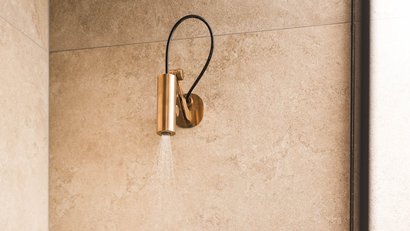 Moderne Duscharmaturen in goldener Ausführung an beiger Wand