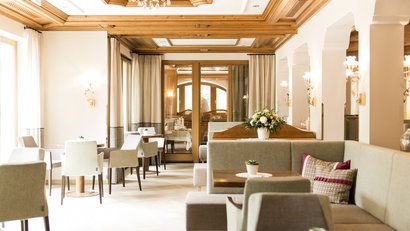 Helles, gemütliches Restaurant mit Holzbalkendecke und gedeckten Tischen