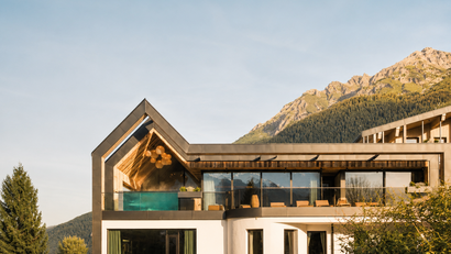 Modernes Haus mit Glasfront und Bergblick im Sonnenlicht