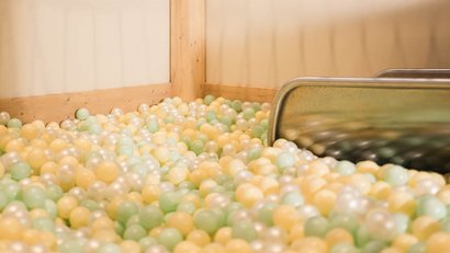 Leerer Bällebadbereich mit pastellfarbenen Bällen und Metallrutsche