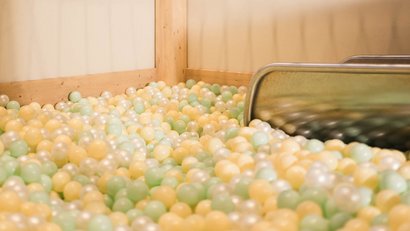Empty ball pit with pastel balls and metal slide in corner