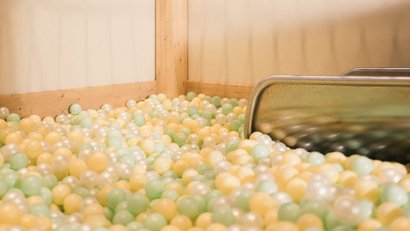 Leerer Bällebadbereich mit pastellfarbenen Bällen und Metallrutsche