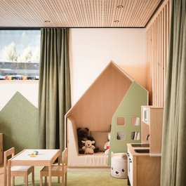 Kinderzimmer mit Spieltisch, Holzküche und Kuschelecke im Hausdesign