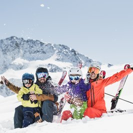 Familie beim Skifahren im Schnee vor schneebedeckten Bergen