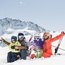 Familie beim Skifahren im Schnee vor schneebedeckten Bergen
