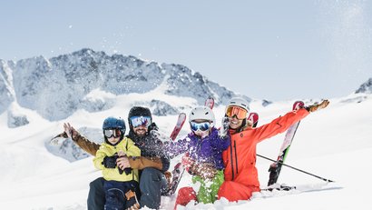 Familie beim Skifahren im Schnee vor schneebedeckten Bergen