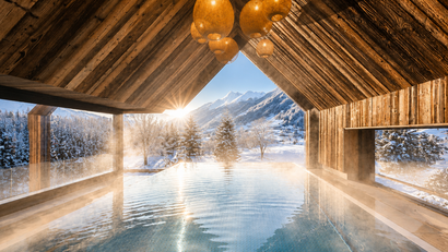 Beheizter Pool unter einem Holzdach mit Blick auf verschneite Berge im Sonnenaufgang