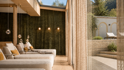 Helle Lounge mit bequemen Sesseln und Blick auf Terrasse und Berge