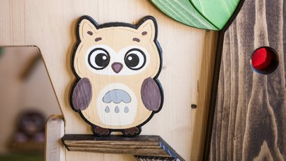 Holzeule mit großen Augen an einer Holzwand montiert