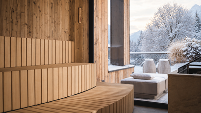 Holzsauna mit breiten Bänken und Blick auf eine verschneite Terrasse