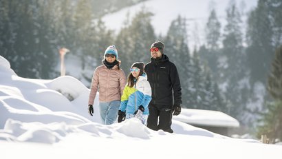 Familie spaziert im Schnee in den Bergen bei Sonnenschein