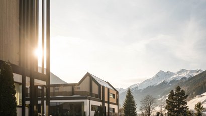 Haus vor schneebedeckten Bergen und sonnigem Himmel