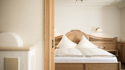 Gemütliches Schlafzimmer mit Holzmöbeln und zwei weißen Kissen auf dem Bett