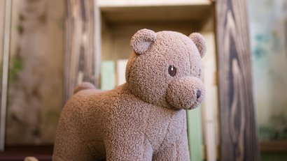 Plüsch-Tier Schaukelspielzeug vor einem bemalten Holzhaus im Innenraum