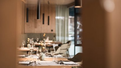 View through door of modern, neatly set restaurant tables with warm lighting