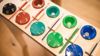 Bunte Pinsel und Farbschalen auf einem Tisch angeordnet