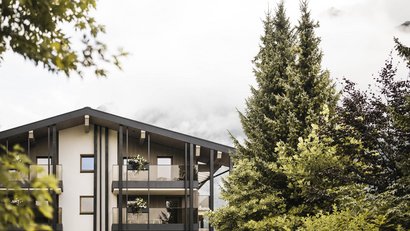 Wohnhaus mit Balkonen und grünen Bäumen im Nebel