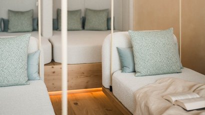 White seating area with green pillows and open book on blanket
