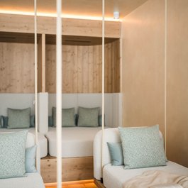 Weißer Sitzbereich mit grünen Kissen und offenem Buch auf Decke